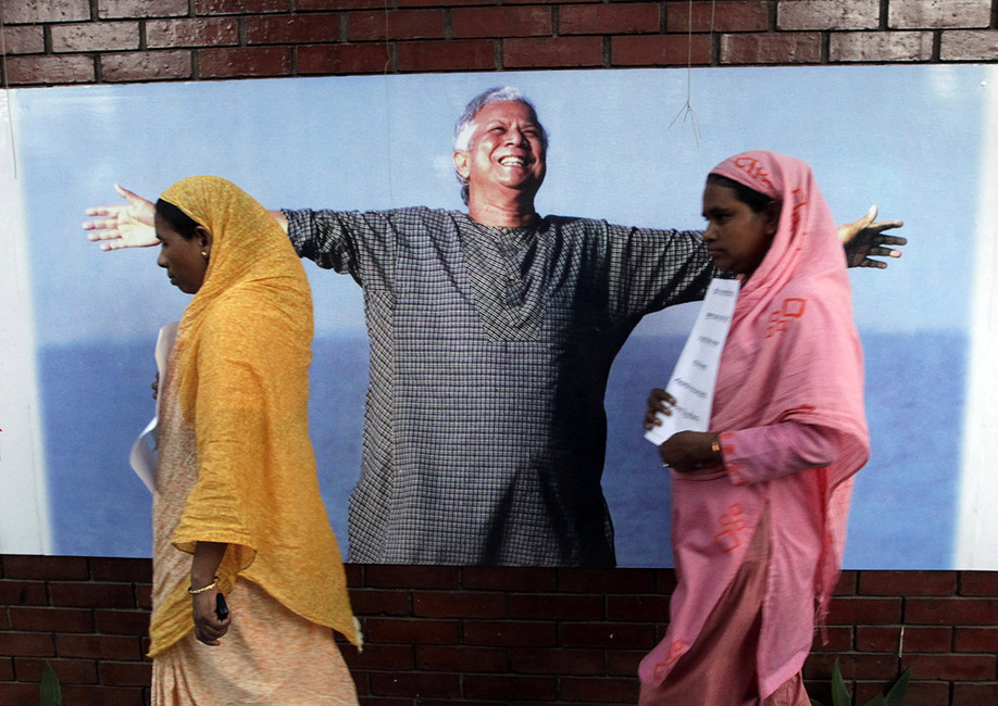 Сотрудники Grameen bank на фоне его основателя Мухаммада Юнуса Фото: Andrew Biraj / Reuters