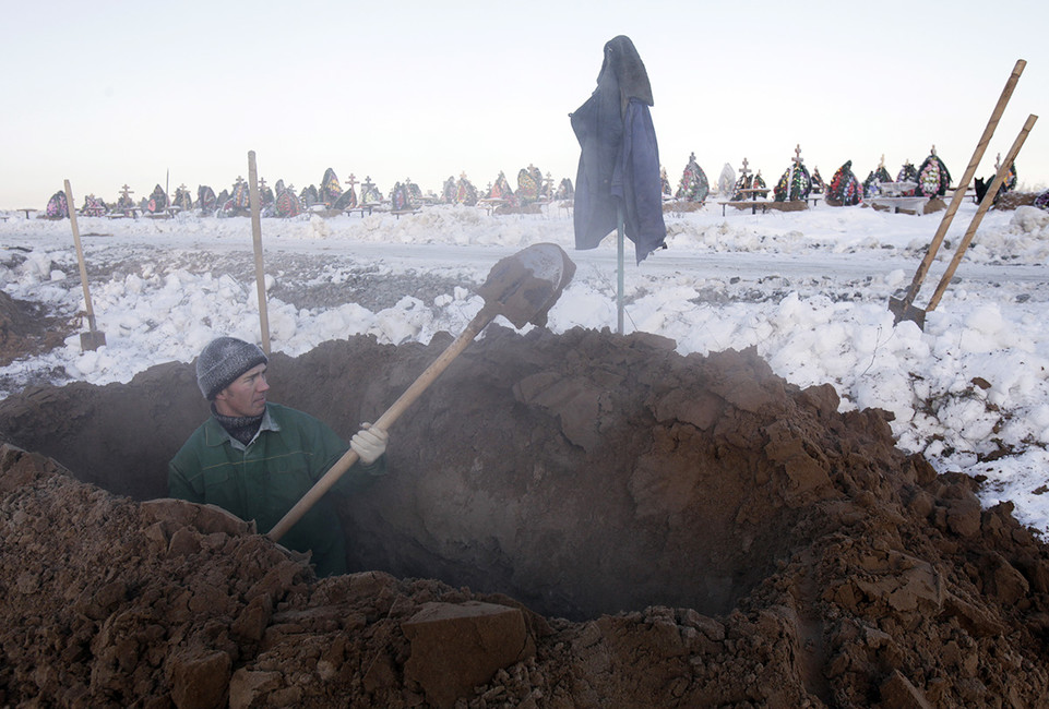 Рабочий копает могилу на кладбище. Фото: Денис Синяков / Reuters